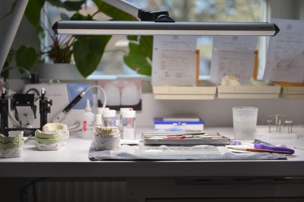 Arbeitsplatz im praxiseigenen Zahnlabor: Gipsmodelle, Zahnfarbmuster und Werkzeug unter der Arbeitsleuchte