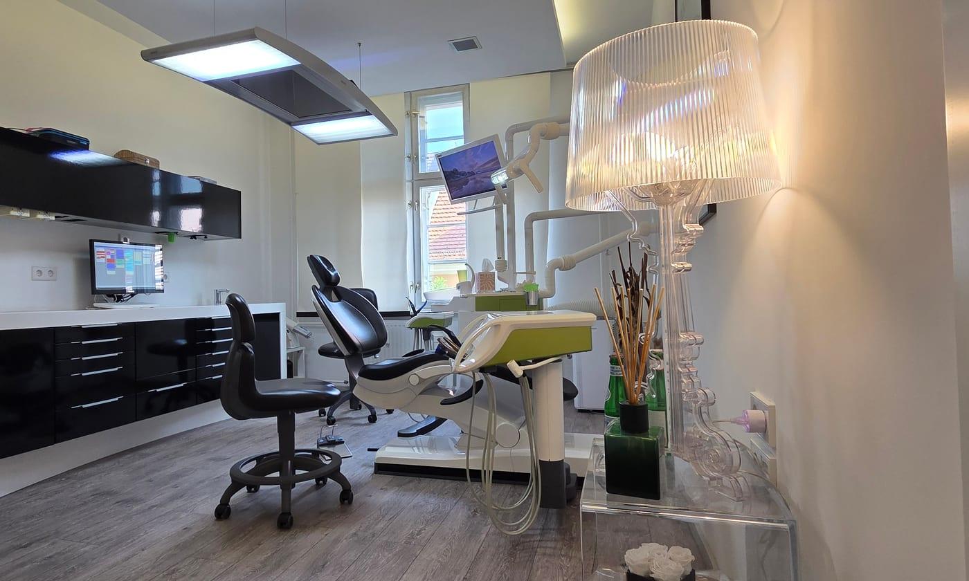 Behandlungszimmer mit Stuhl, Deckenleuchte und Fenster in der Zahnarztpraxis Groß & Groß