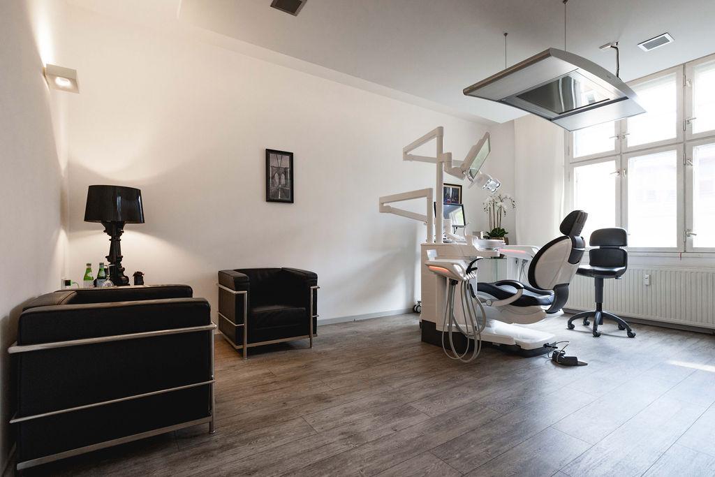 Behandlungszimmer mit Sitzecke, hohen Fenstern und Behandlungsstuhl