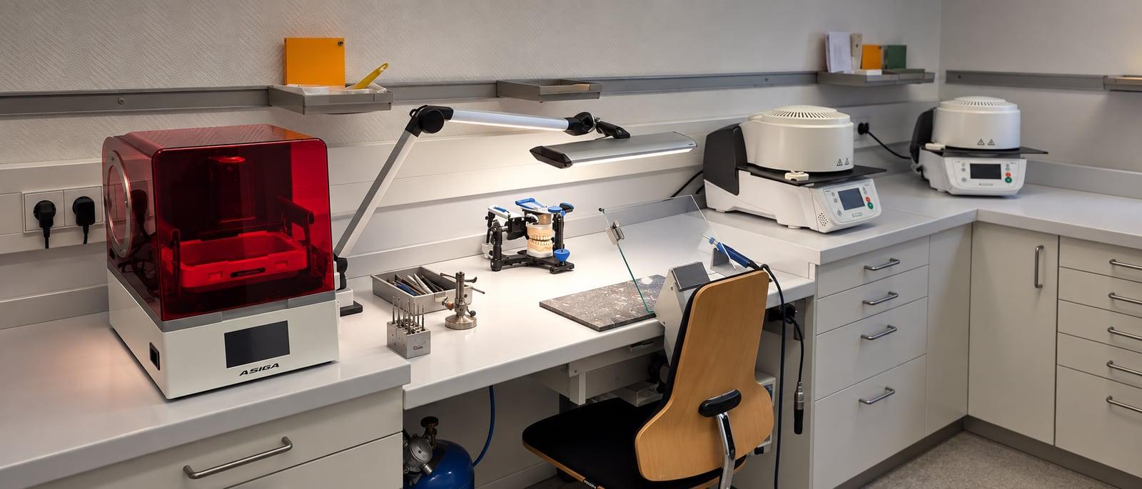 Werkbank im praxiseigenen Zahnlabor mit 3-D-Drucker und Artikulator